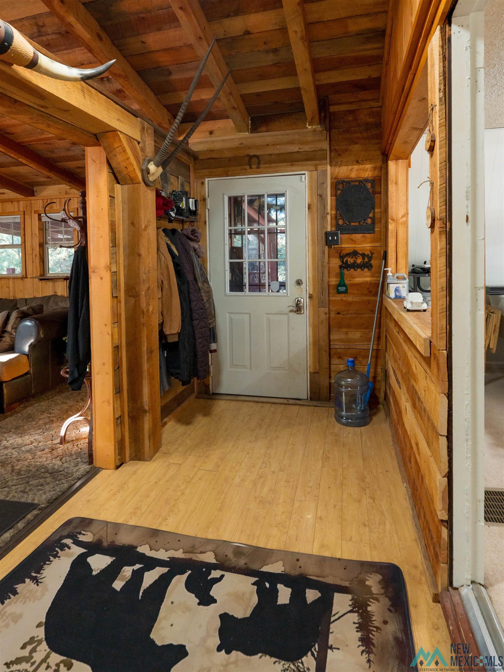 3 Wimsatt Road Cloudcroft, NM 88317 - Photo 3 of 41 Interior space with wood walls, light wood-style flooring, plenty of natural light, and a wooden ceiling with exposed beams