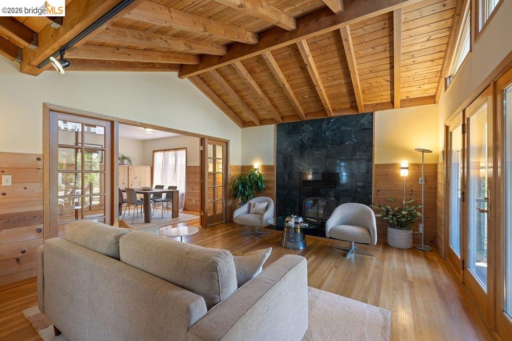287 Purdue Avenue Kensington, CA 94708 - Photo 12 of 60 Living area featuring a vaulted wood-plank ceiling, wood-finish flooring, a dark stone fireplace, and wood-paneled walls
