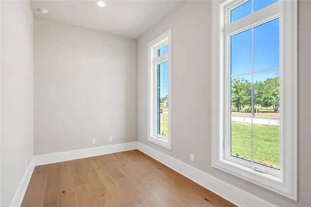 an empty room with chandelier fan and windows