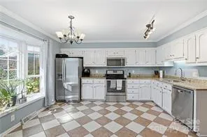 a kitchen with stainless steel appliances granite countertop a refrigerator a sink dishwasher a stove and white cabinets with wooden floor