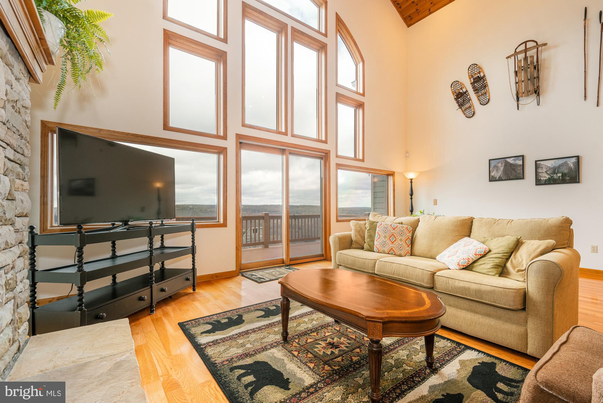 750 Wisp Mountain Road, Unit B McHenry, MD 21541 - Photo 10 of 49 a living room with furniture a flat screen tv and a floor to ceiling window