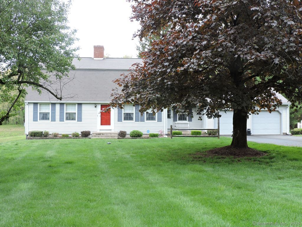 a front view of a house with yard and tree