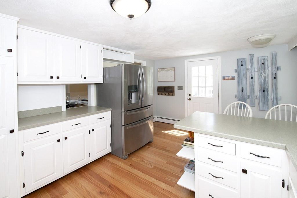 49 Moffatt Road Salem, MA 01970 - Photo 5 of 25 a kitchen with granite countertop a refrigerator a stove and white cabinets with wooden floor