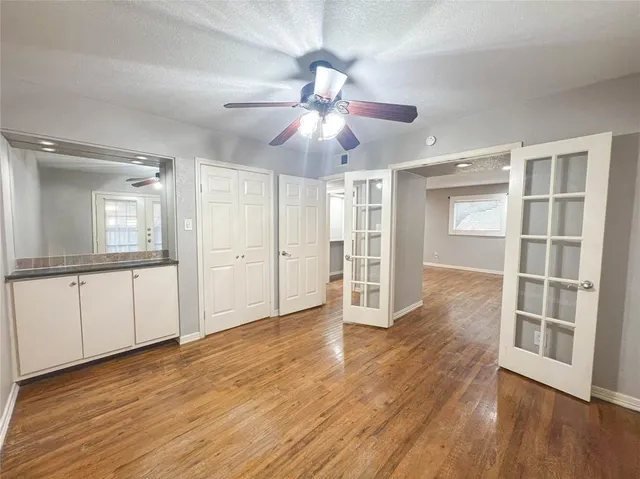 a view of an empty room with wooden floor and a ceiling fan