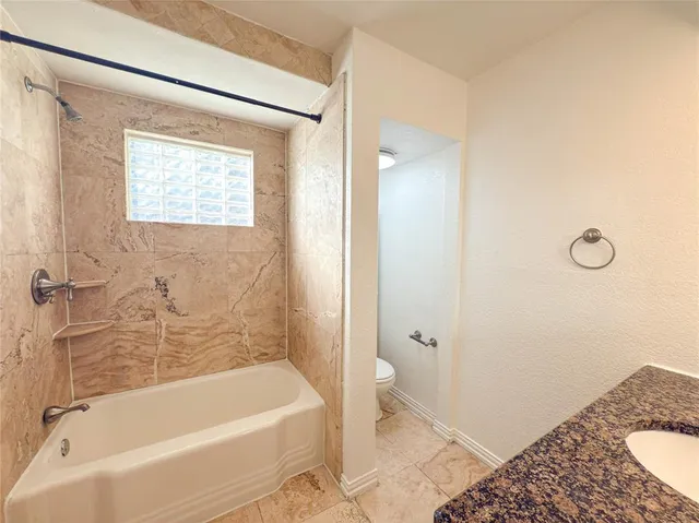 a bathroom with a granite countertop sink a toilet and bathtub
