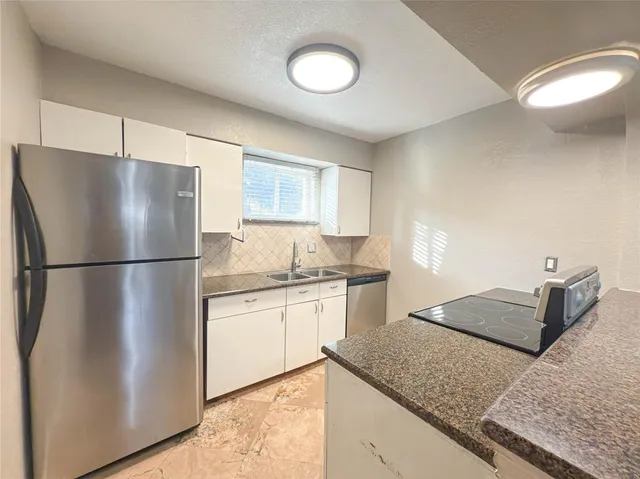 a kitchen with stainless steel appliances granite countertop a refrigerator a sink a stove a dining table and chairs