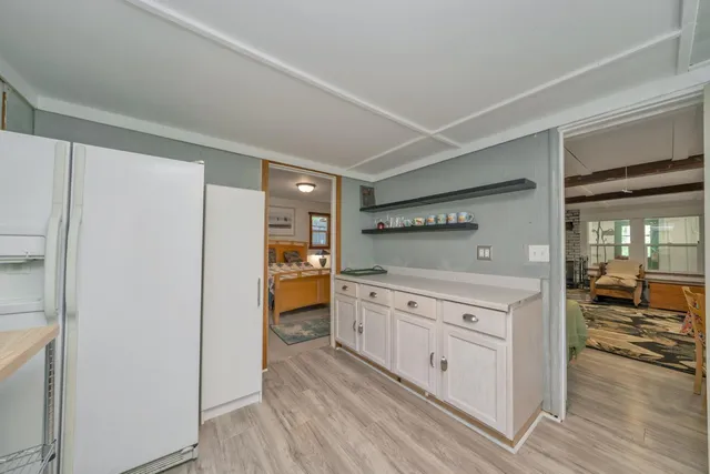 a kitchen with white cabinets and wooden floor