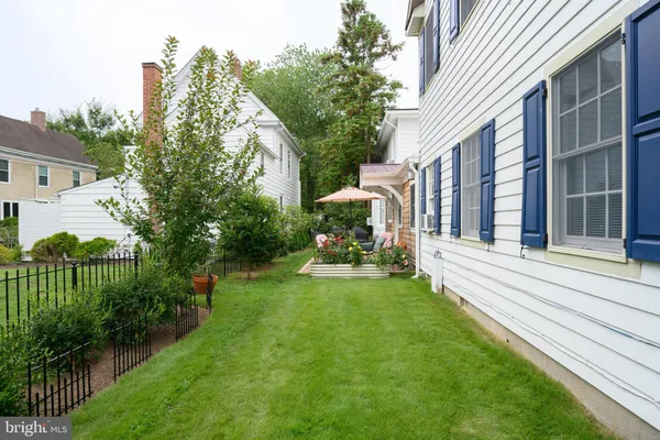 a backyard of a house with table and chairs under an umbrella