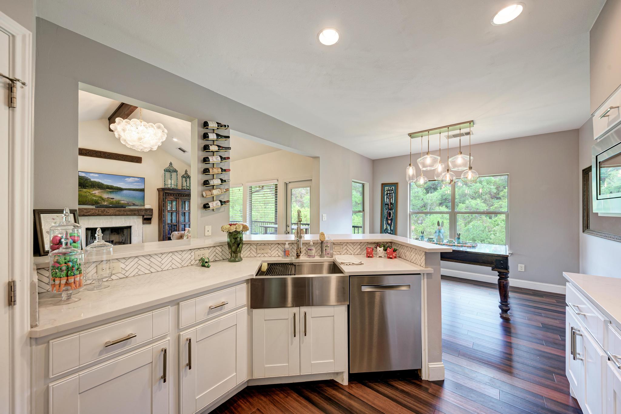 2605 Indian Creek Road Austin, TX 78734 - Photo 8 of 33 White kitchen cabinetry with stainless steel farmhouse sink and integrated dishwasher