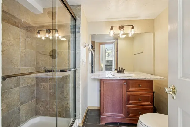 a bathroom with a granite countertop sink a toilet and shower