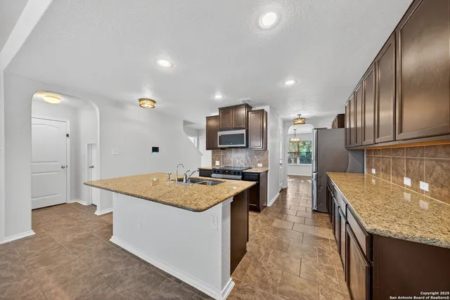 a kitchen with stainless steel appliances granite countertop a sink stove and refrigerator