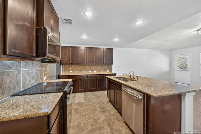 a kitchen with stainless steel appliances granite countertop a sink stove and refrigerator