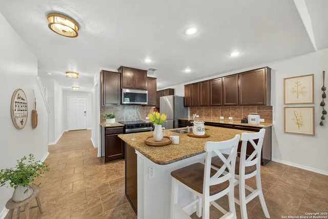 a kitchen with stainless steel appliances granite countertop a stove top oven a refrigerator a sink and a stove