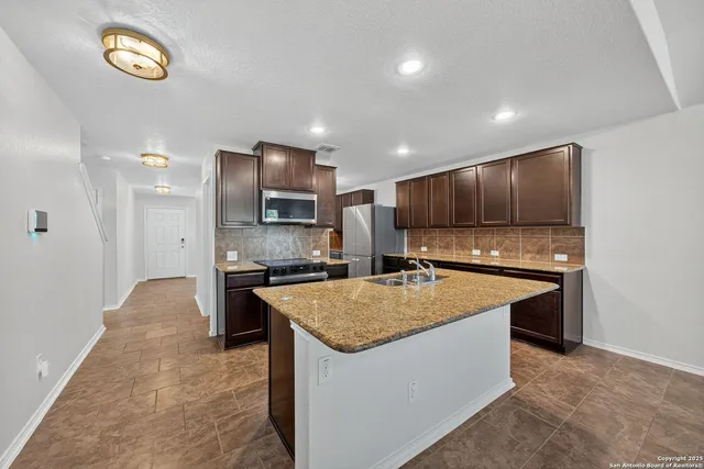 a kitchen with stainless steel appliances granite countertop a sink stove and refrigerator