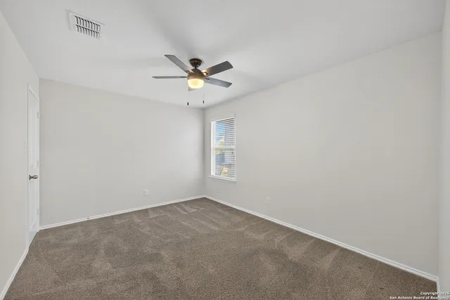 an empty room with a window and a fan