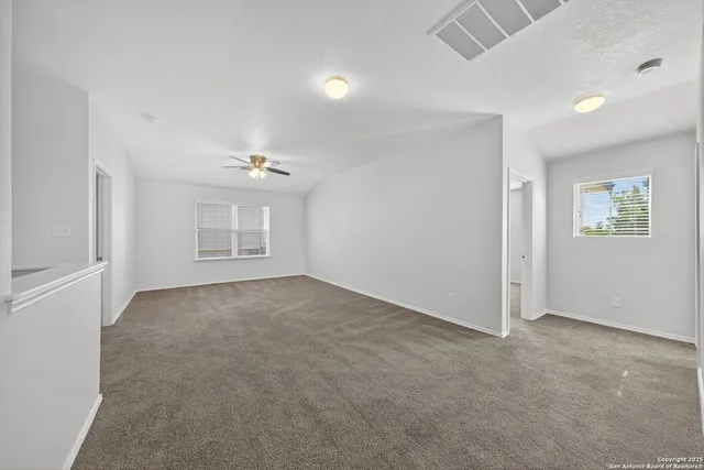 an empty room with windows and ceiling fan