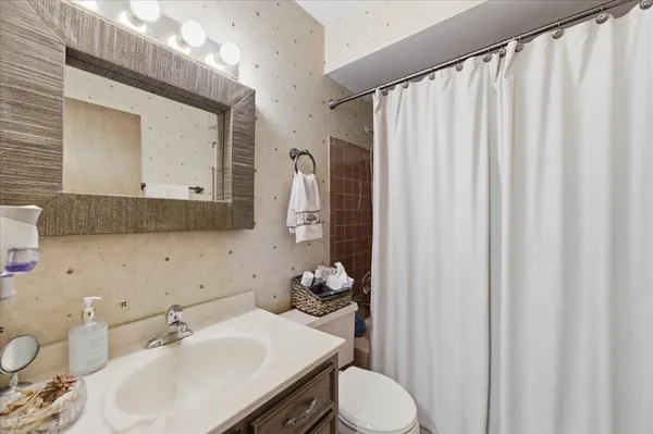 a bathroom with a sink a toilet and shower curtain
