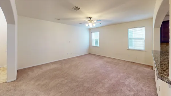 an empty room with a chandelier fan and windows