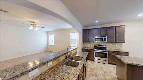 a kitchen with stainless steel appliances granite countertop a sink dishwasher stove top oven and cabinets