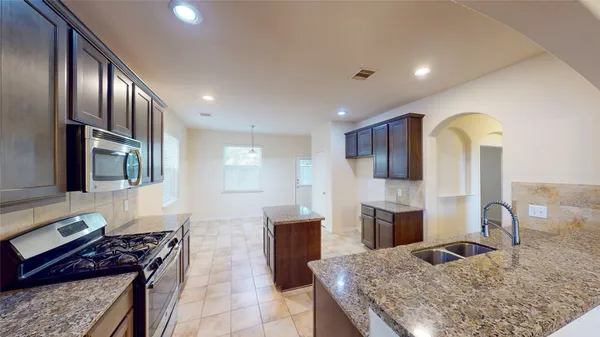a kitchen with stainless steel appliances granite countertop a stove refrigerator and cabinets