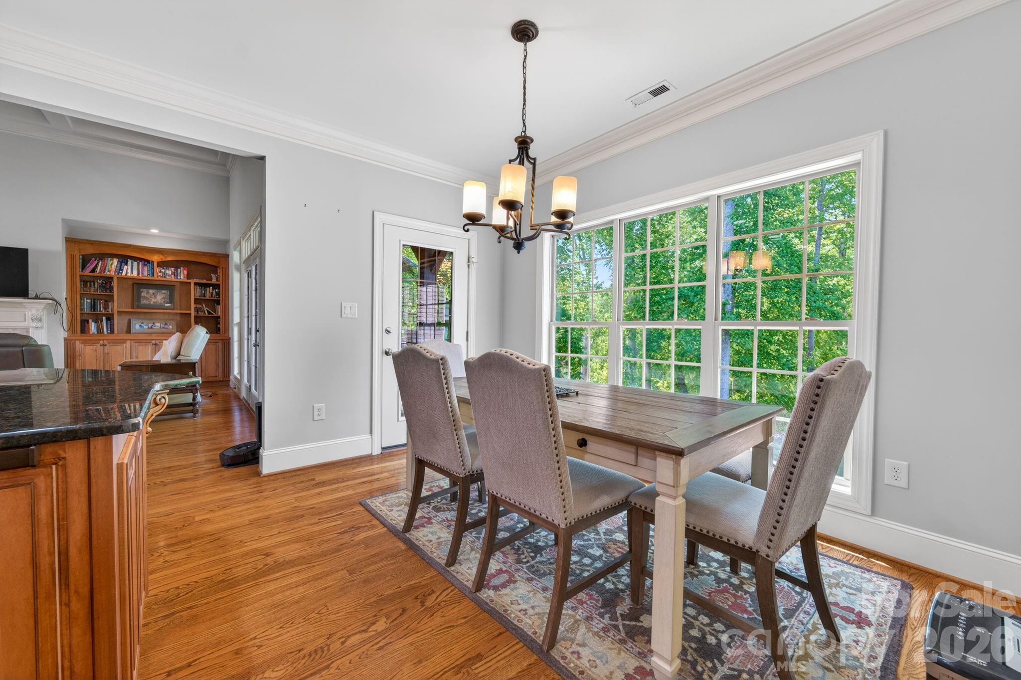 3138 Rappahannock Court, Unit 16 Matthews, NC 28104 - Photo 6 of 38 a dining room with wooden floor a chandelier a glass table and chairs