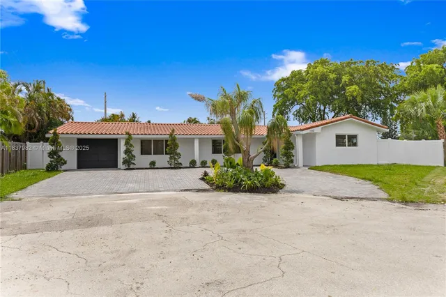 a front view of a house with a yard and potted plants