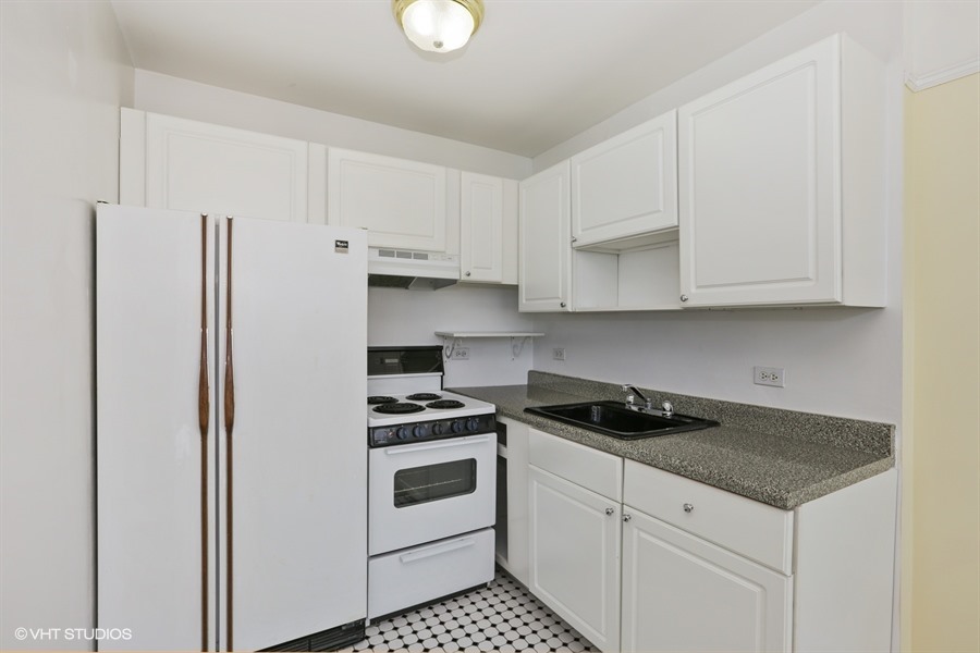 6171 North Sheridan Road, Unit 1107 Chicago, IL 60660 - Photo 6 of 18 a kitchen with white cabinets and white appliances