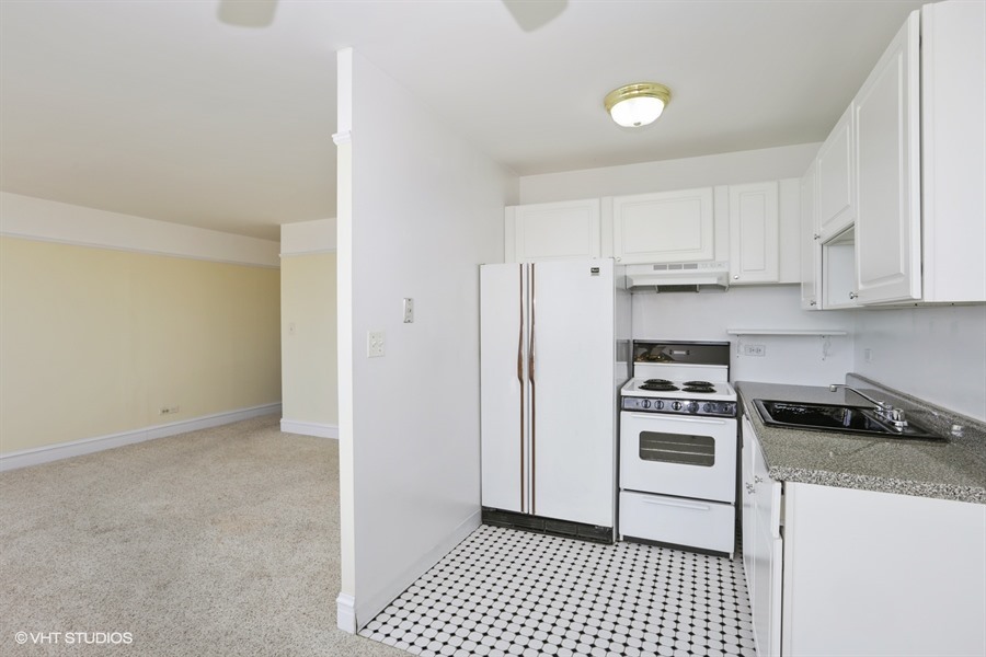 6171 North Sheridan Road, Unit 1107 Chicago, IL 60660 - Photo 8 of 18 a kitchen with granite countertop a stove a sink and a refrigerator