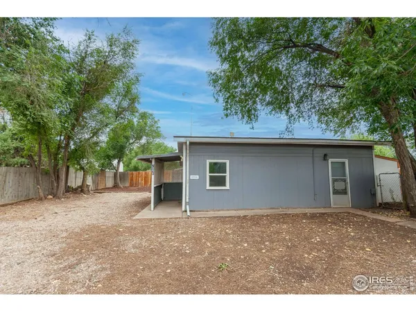 a backyard of a house with large tree and wooden fence
