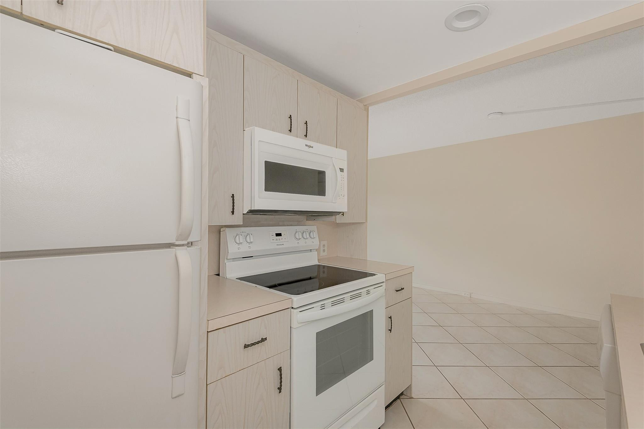 2009 Cornwall Drive, Unit 2009 Boca Raton, FL 33434 - Photo 8 of 23 a kitchen with white cabinets and white appliances