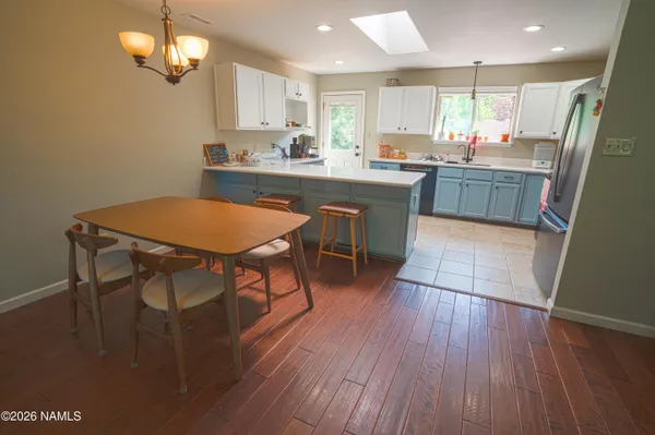 a kitchen with stainless steel appliances a dining table chairs stove refrigerator and cabinets