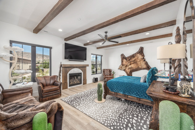 168 South Rancho Santa Fe Virgin, UT 84779 - Photo 17 of 68 High ceilings with exposed wood beams, multiple windows with dark trim, a built-in fireplace with a stone surround, and wood-finish flooring