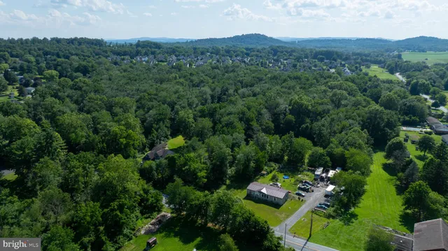 an aerial view of residential house with outdoor space and trees all around
