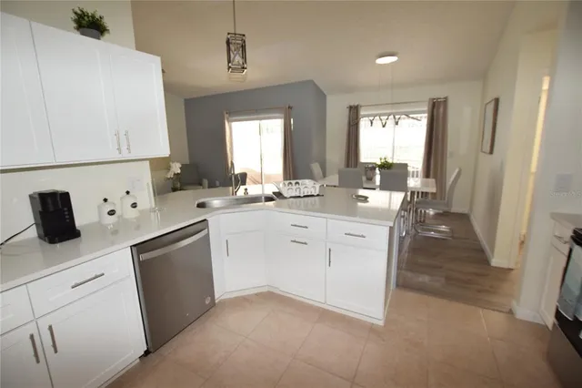 a kitchen with white cabinets a sink dishwasher and a stove with wooden floor