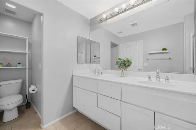a bathroom with a double vanity sink mirror and toilet