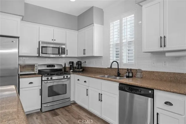 a white kitchen with granite countertop white cabinets and white stainless steel appliances