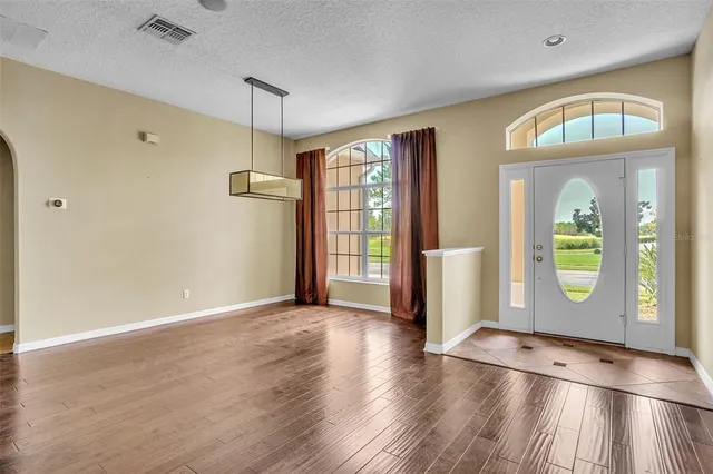 a view of an empty room with window and wooden floor