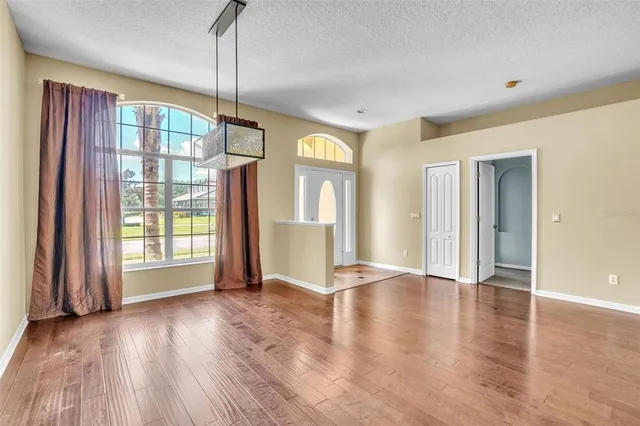 a view of an empty room with glass door and wooden floor