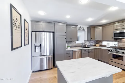 a living room with stainless steel appliances kitchen island granite countertop furniture and wooden floor