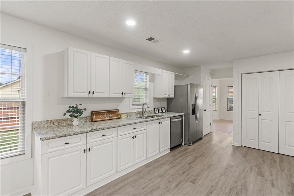 3003 Brass Drive Austell, GA 30106 - Photo 7 of 26 a kitchen with stainless steel appliances granite countertop a stove a sink and white cabinets with wooden floor
