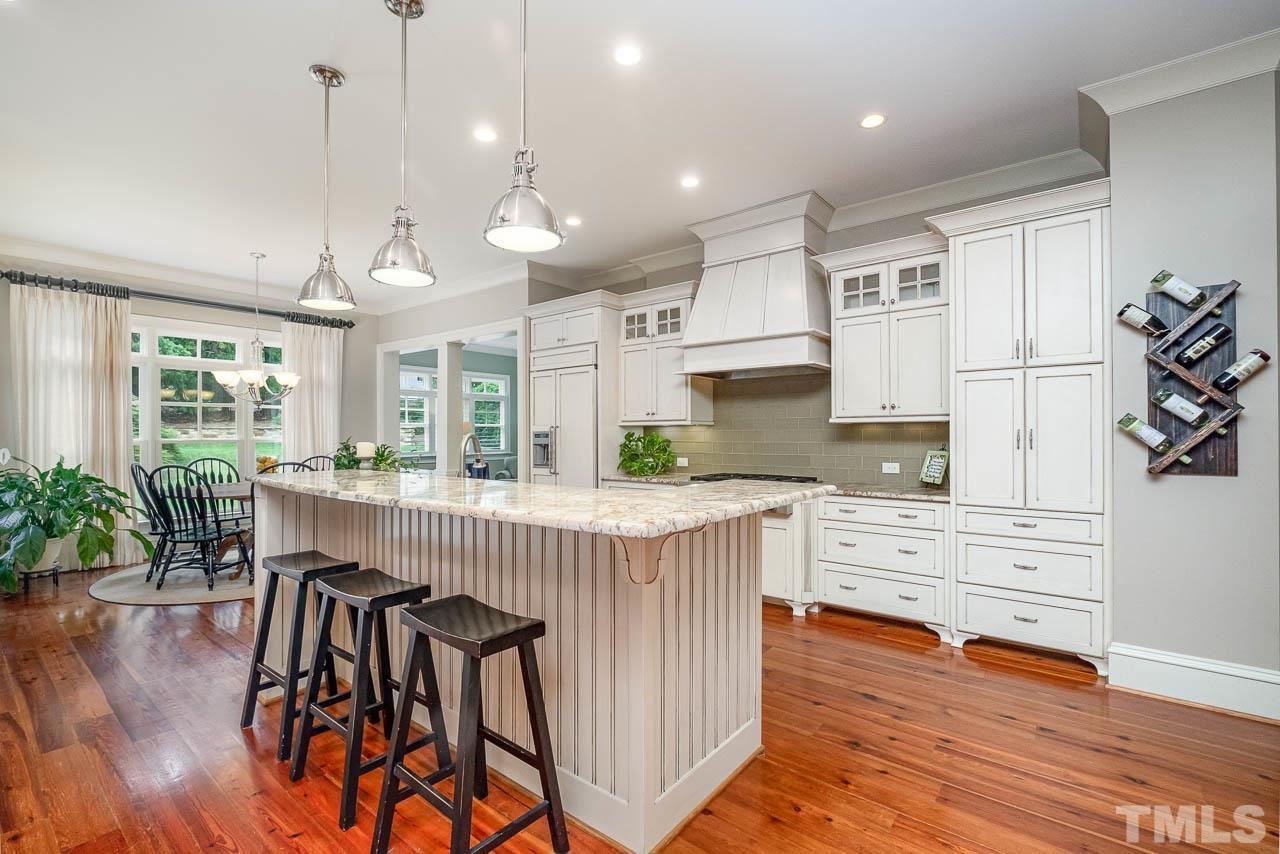 2129 Buckingham Road Raleigh, NC 27607 - Photo 20 of 52 a kitchen with stainless steel appliances kitchen island wooden floors refrigerator stove and white cabinets