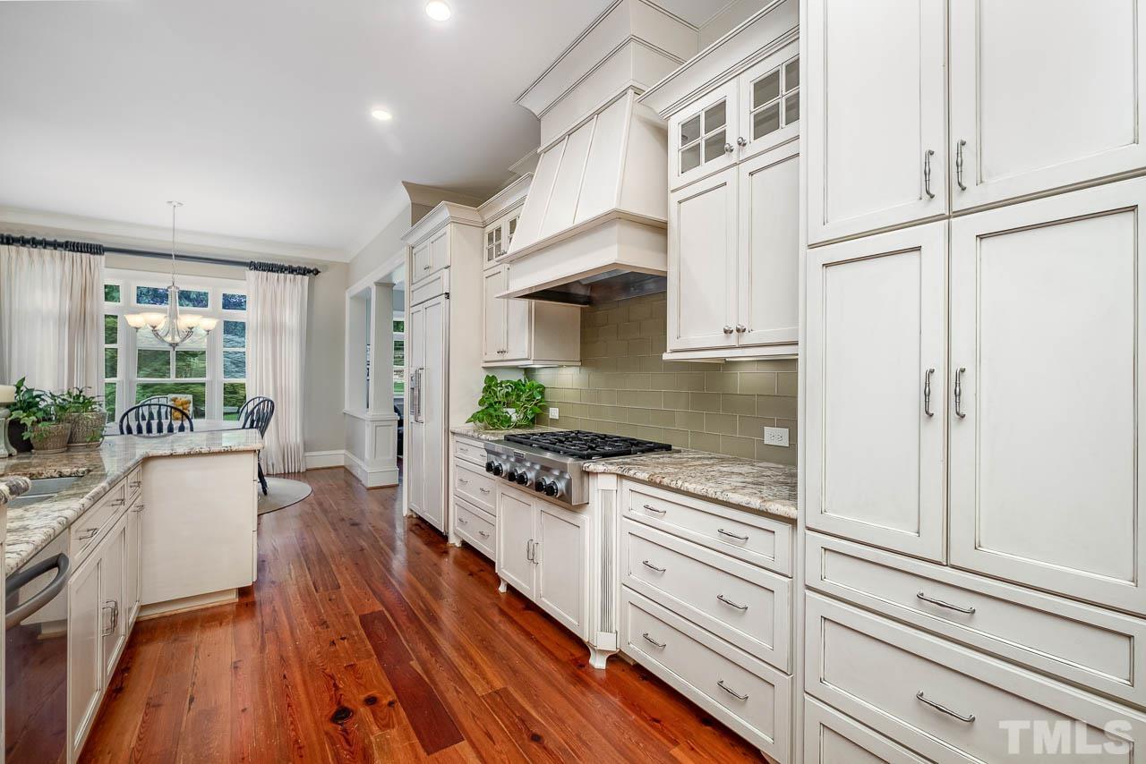 2129 Buckingham Road Raleigh, NC 27607 - Photo 21 of 52 a kitchen with stainless steel appliances white cabinets and wooden floors