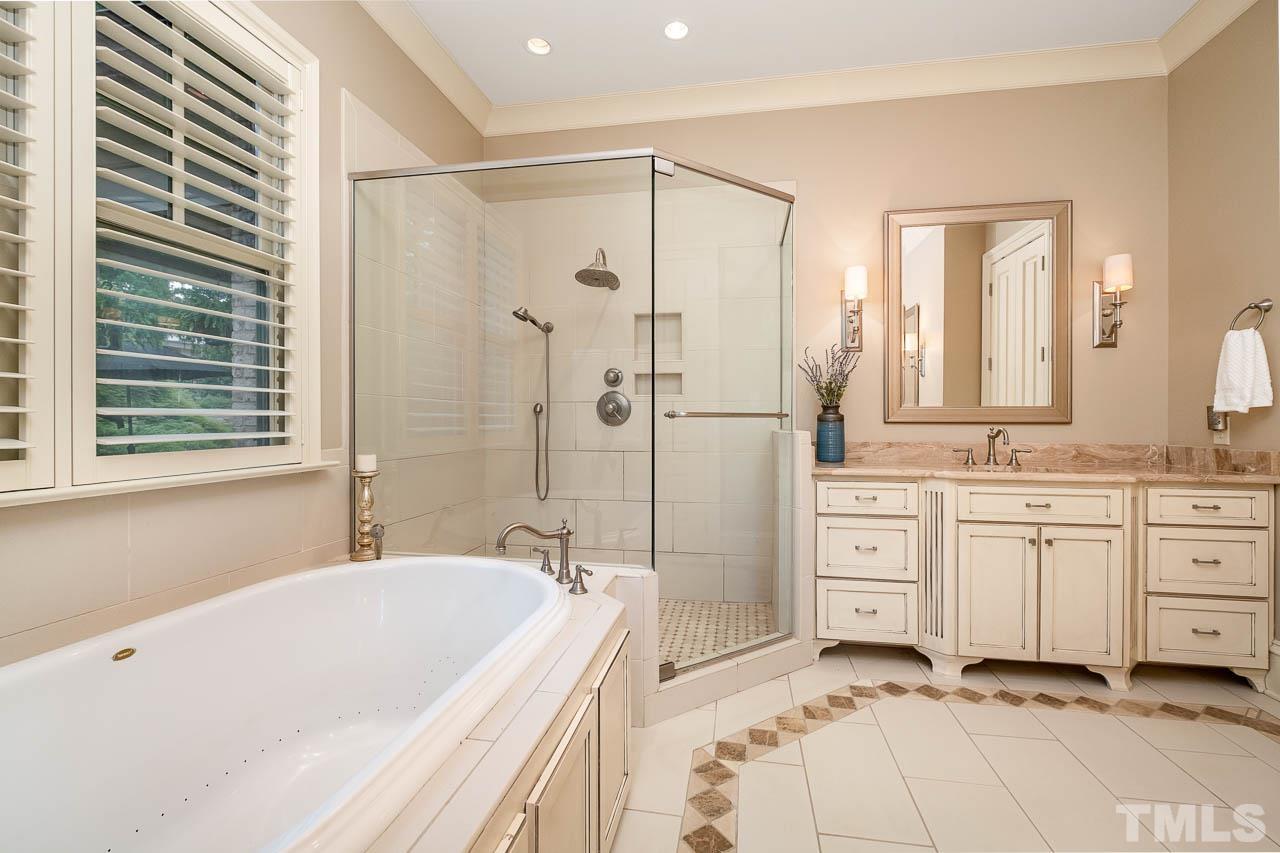 2129 Buckingham Road Raleigh, NC 27607 - Photo 32 of 52 a spacious bathroom with a granite countertop tub sink a mirror a shower and vanity