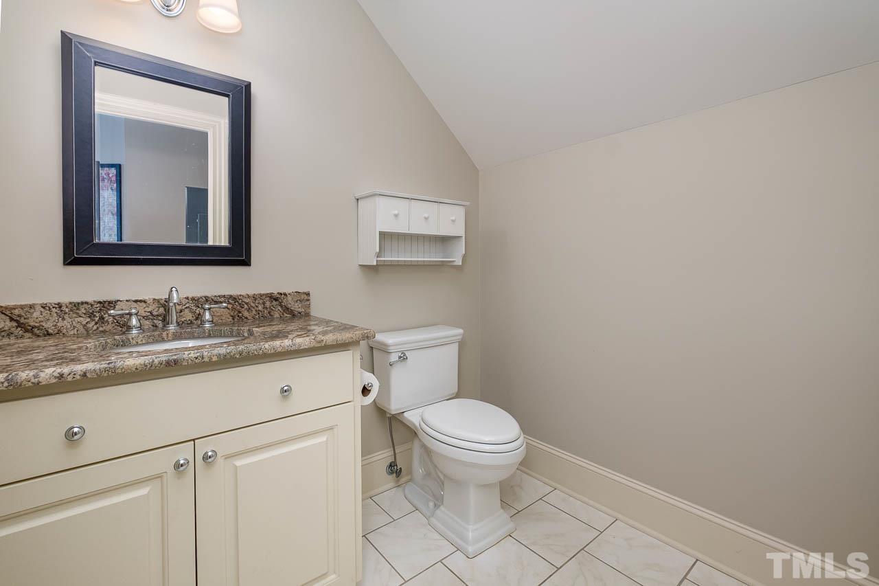 2129 Buckingham Road Raleigh, NC 27607 - Photo 36 of 52 a bathroom with a granite countertop toilet a sink and a mirror