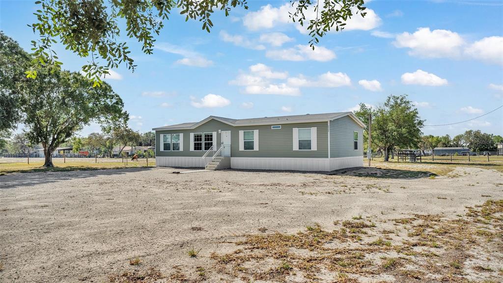 5535 Lake Buffum Road Lake Wales, FL 33859 - Photo 4 of 48 a front view of a house with a dirt yard and a large tree