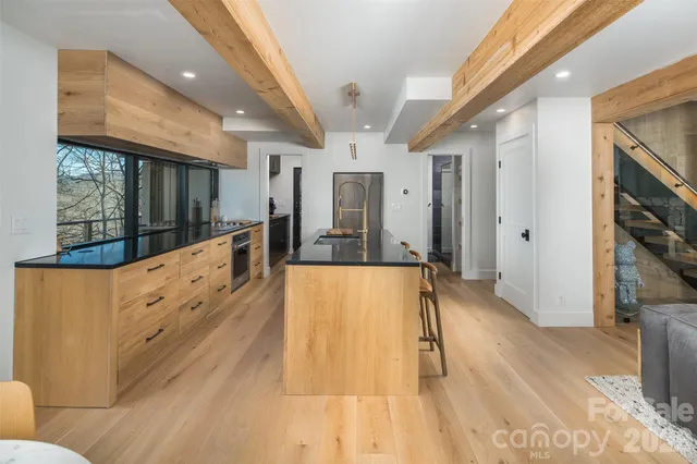 a view of living room kitchen with stainless steel appliances wooden floor and large window