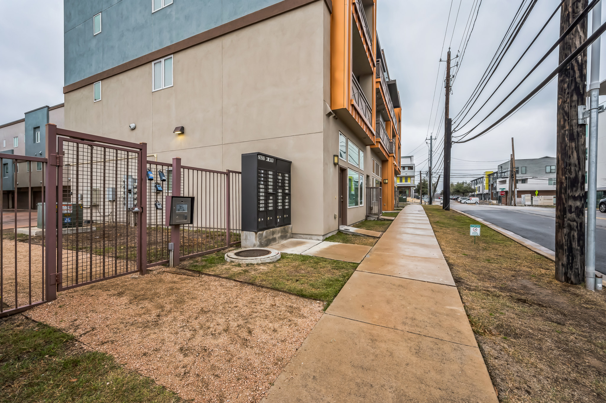 2827 Manor Road, Unit 3104 Austin, TX 78722 - Photo 19 of 30 Gated entry leads to a contemporary multi-story building with a well-maintained sidewalk.