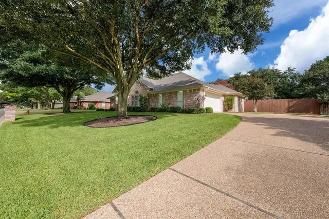 a view of a house with a big yard potted plants and large tree