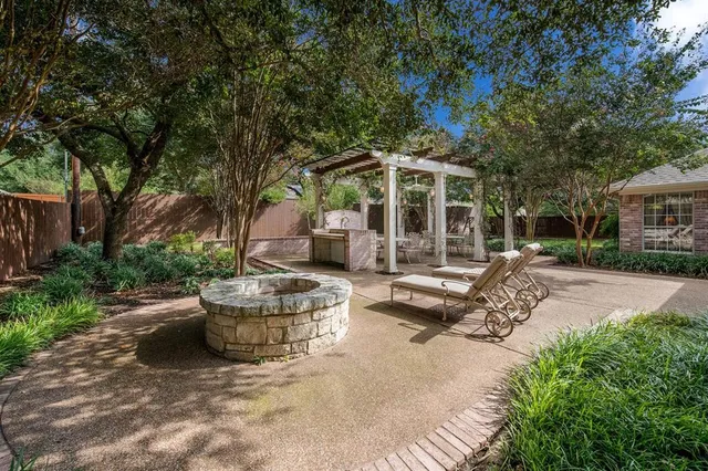 a view of a patio with table and chairs potted plants and large tree