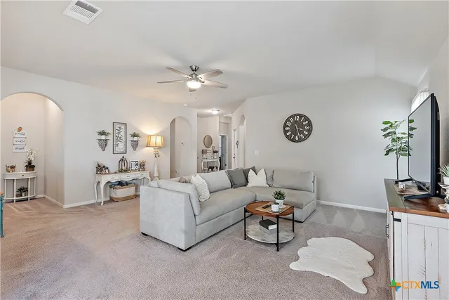 a living room with furniture kitchen view and a chandelier